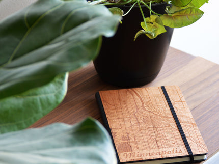 Wooden notebook with 'Minneapolis' engraving on a wooden surface with a plant in the background