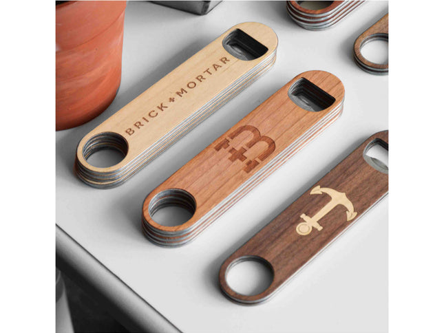 Wooden bottle openers with engraved designs on a white surface