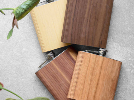 Three wooden flasks on a textured surface with green leaves.