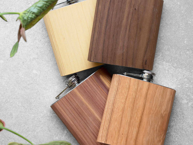 Three wooden flasks on a textured surface with green leaves.