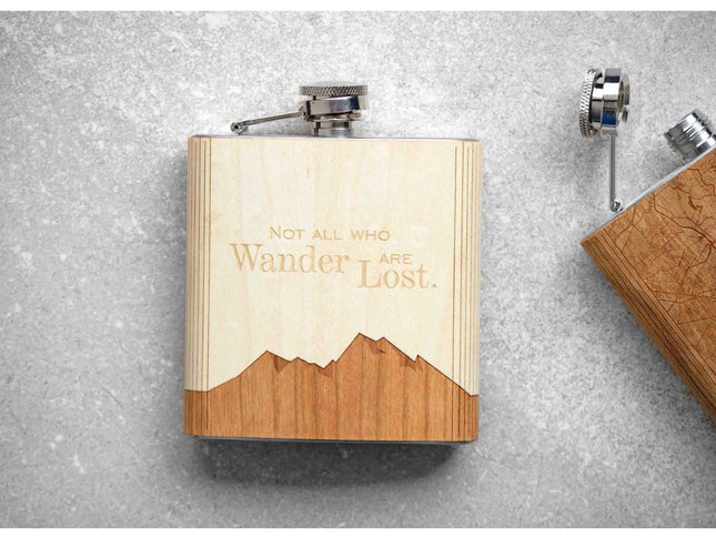 Wooden flask with mountain design and engraved text on a gray surface