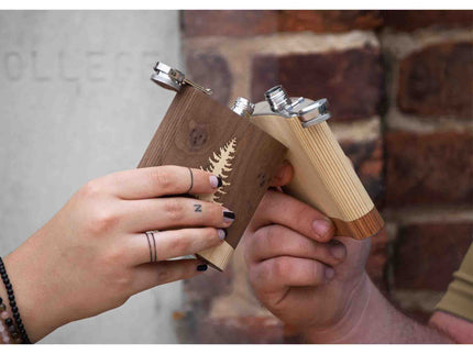 Two wooden guns held by hands against a brick wall.