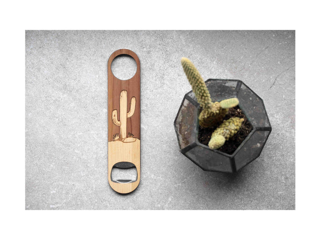 Bottle opener with cactus design next to a small potted cactus on a gray surface