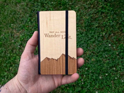 Wooden notebook held in a hand with grass in the background
