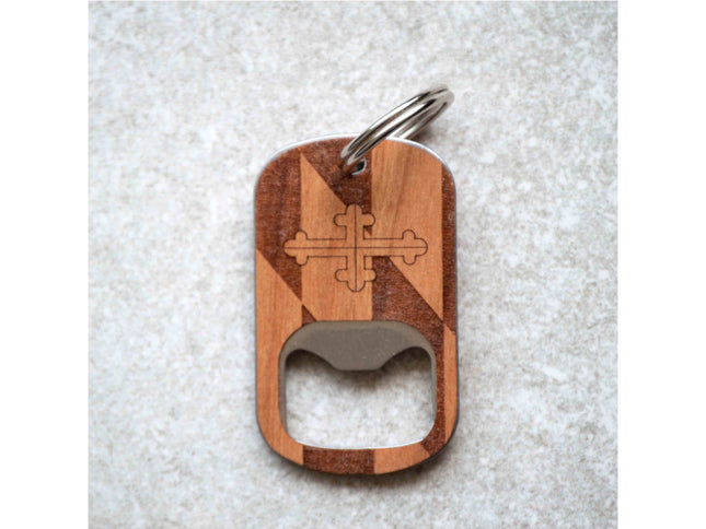 Wooden bottle opener keychain with a cross design on a textured surface