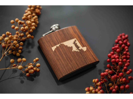Wooden flask with inlaid Maryland state design on a dark surface with berries