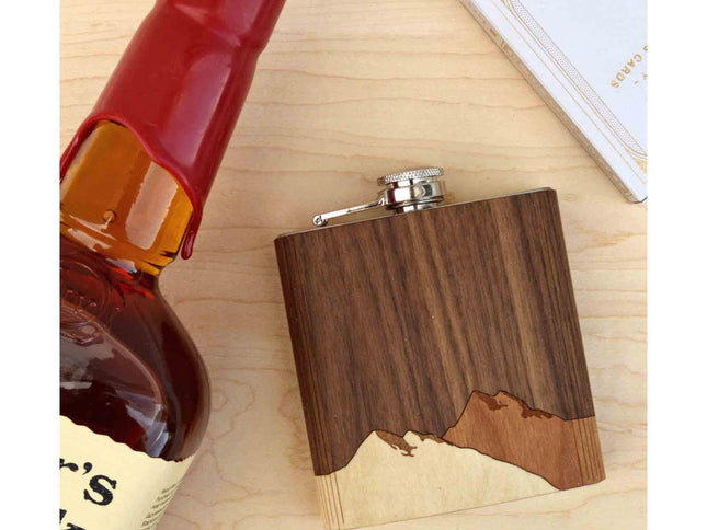 Wooden flask on a wooden surface next to a bottle of Maker's Mark bourbon.
