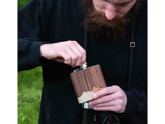 Person holding a wooden hip flask outdoors