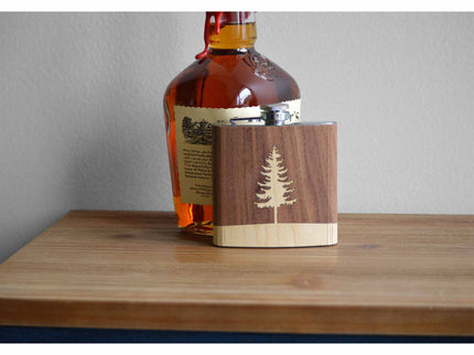 Bottle of whiskey with a wooden tumbler on a wooden surface