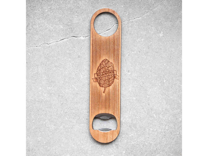 Wooden bottle opener with engraved design on a gray concrete surface