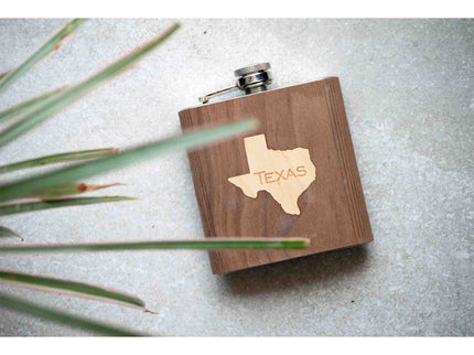 Wooden flask with Texas outline on a textured surface with grass.