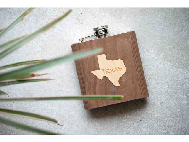 Wooden flask with Texas outline on a textured surface with grass.