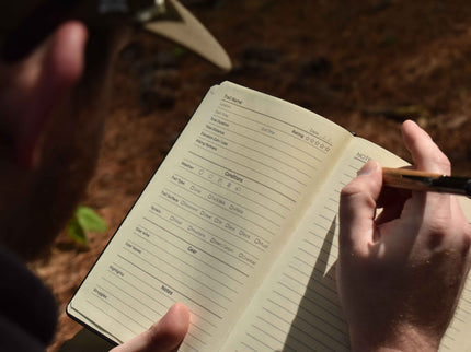 Person holding a notebook with a pen, outdoors