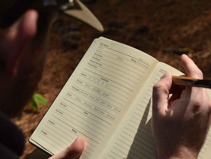 Person holding a notebook with a pen, outdoors