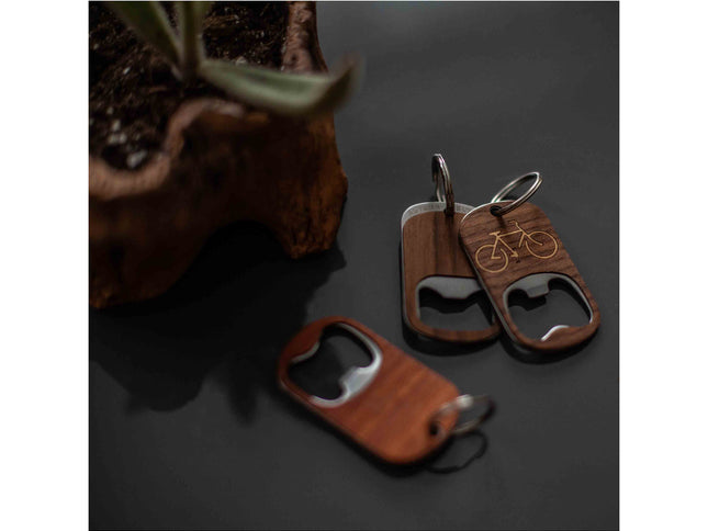 Wooden bottle opener keychains with bicycle design on a dark surface