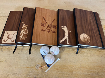 Four wooden golf-themed notebooks with golf-related illustrations on a wooden surface.