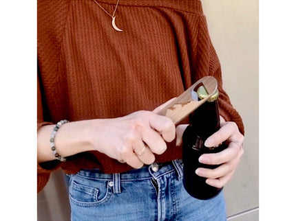 Person opening a bottle with a bottle opener in a casual setting