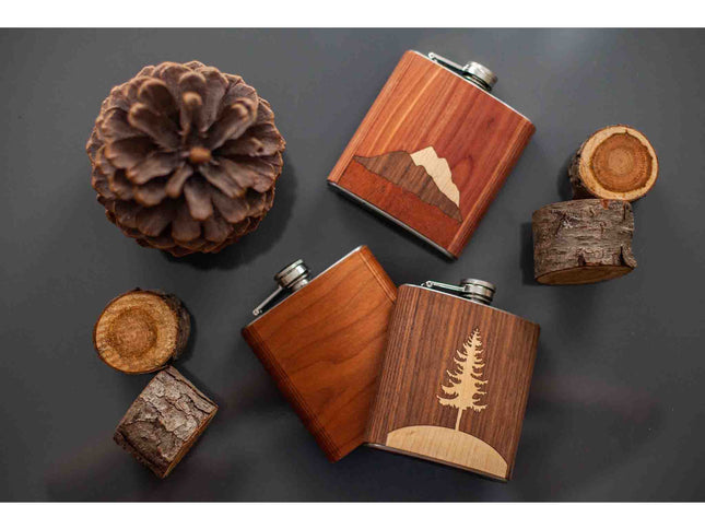 Wooden flasks with nature-themed designs on a dark surface