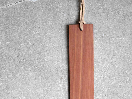 wood bookmark with leather loop against stone backdrop.