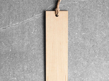 Wood bookmark with leather loop against grey stone background.