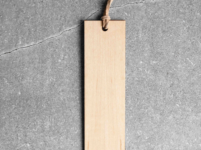 Wood bookmark with leather loop against grey stone background.
