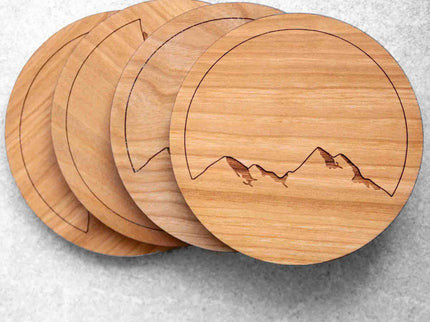 Set of 4 real wood cherry coasters with mountain range design on stone background.