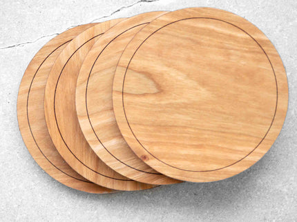 A set of four round wooden coasters made of jatoba cherry wood, placed on a grey surface.