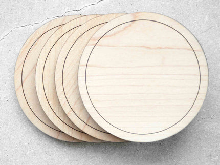 A set of four round hard maple wood coasters placed on a stone surface