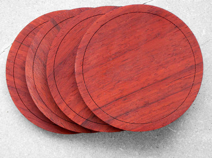 A set of four padauk wood coasters placed on stone surface