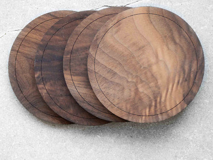 A set of 4 black walnut wood coasters on stone background